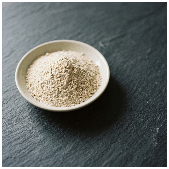 A pale ceramic dish of finely milled colloidal oat powder on slate